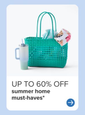 A teal beach bag with towels in it beside a big water cup.
