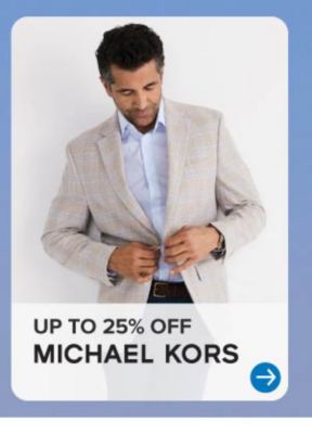 A man buttons his Michal Kors sport coat. Up to 25% off Michael Kors.