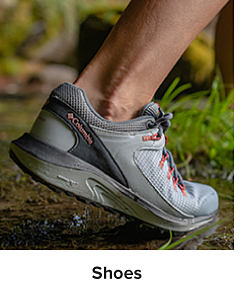 A gray Columbia trail running shoe, mid stride on a wet trail. Shoes. 