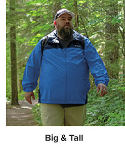 Man in the woods wearing a blue and black raincoat. Big and tall.