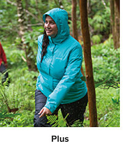 Woman in the woods wearing a teal raincoat and black pants. Plus.