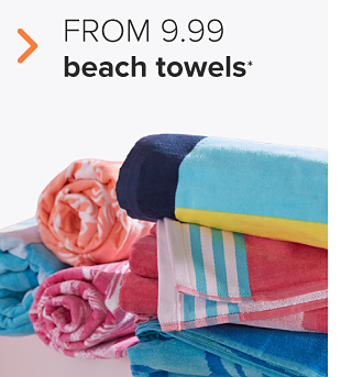 Rolled up beach towels in different patterns and colors. Up to 60% off beach bags and beach towels. 