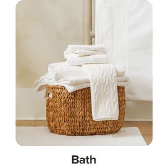 An image of a basket filled with white towels. Shop bath.