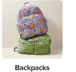 A multi-colored backpack on top of a green backpack. Shop backpacks.