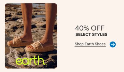 An image of a woman in sandals standing on rocks by the beach. 40% off select styles EARTH.