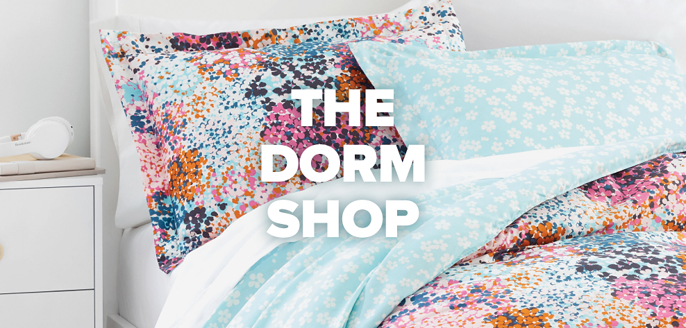 An image of a bed with a colorful abstract print comforter and pillows to match. The Dorm Shop.