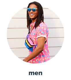 A young man wearing a pink short sleeve button front shirt with a colorful print, a pair of mirrored sunglasses and carrying a color blocked fanny pack with black trim. Men.