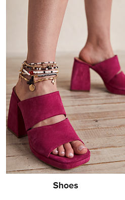 A woman wears pink platform sandals with ankle bracelets. Shoes.