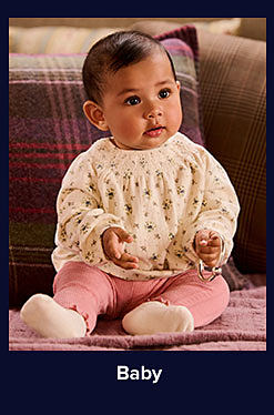 An image of a baby sitting on a couch. Shop baby. 