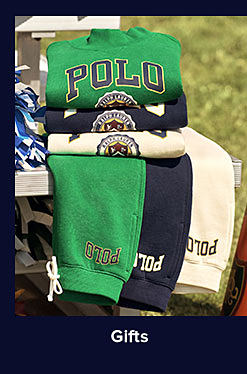 An image Polo Ralph Lauren clothing stacked on a bench. Shop gifts. 