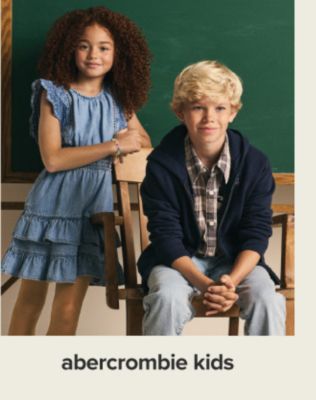 A girl in a blue dress. A boy in blue jeans and a plaid shirt. Shop Abercrombie kids.