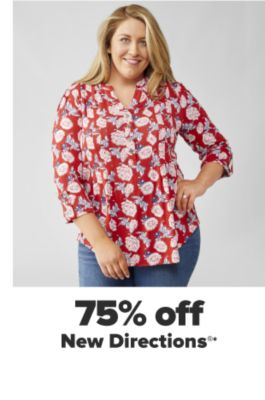 A woman in a red v neck tunic with a white floral pattern and jeans. 75% off New Directions.