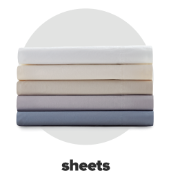 A stack of folded bed sheets in white, ivory, beige, gray and blue. Sheets.
