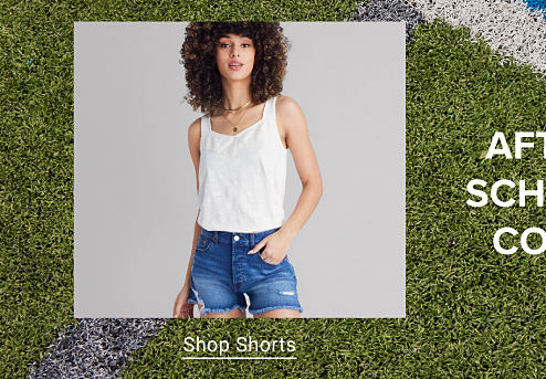 An image of a woman wearing a white top and denim shorts. Shop Shorts.