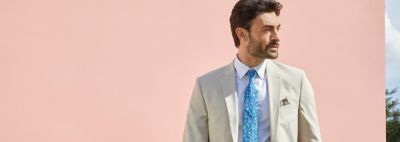 An image of a man wearing a beige suit and blue tie.