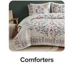 Image of a bed with white bedding with a colorful pattern. Shop comforters.