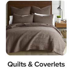 Image of a bed with a brown quilt. Shop quilts and coverlets.