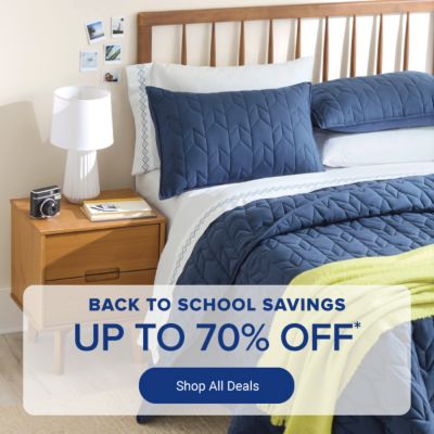 Back to school savings. Up to 70% off. Blue bedding set with pillows and blanket on wooden bed. Shop all deals.