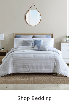 A bed with a white bedspread and white and light blue pillows. Shop bedding.