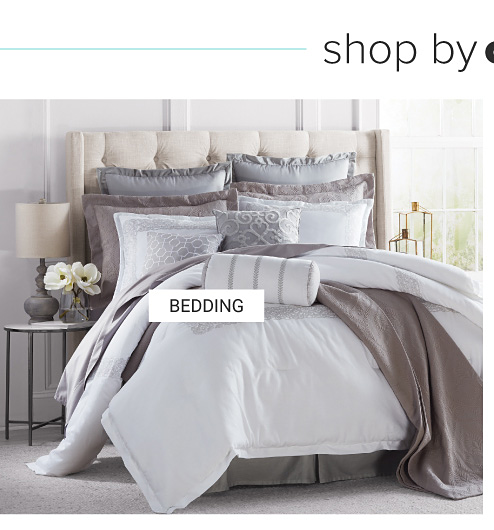 A bed made with a white comforter, a gray quilt & an assortment of gray & white pillows. Shop bedding.