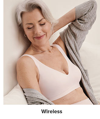 Image of a woman wearing a white bra and gray cardigan. Wireless.
