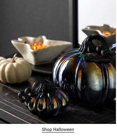 An image of black, iridescent pumpkin decor and candy corn in a dish. Shop Halloween.