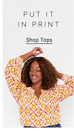 Woman weaing a white blouse with red and orange design. Put it in print. Shop tops.