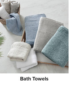 An image of folded towels in blue, gray, white and teal. Shop bath towels.