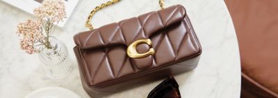 Women's Purses & Handbags. Image of Coach quilted bag on a table.