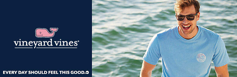 A man by the ocean wearing a blue short sleeve shirt and sunglasses. Vineyard Vines. Every day should feel this good.