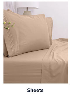 Image of a bed with beige sheets. Shop sheets.
