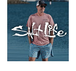 A man in a baseball cap, pink shirt and blue shorts. Salt Life.