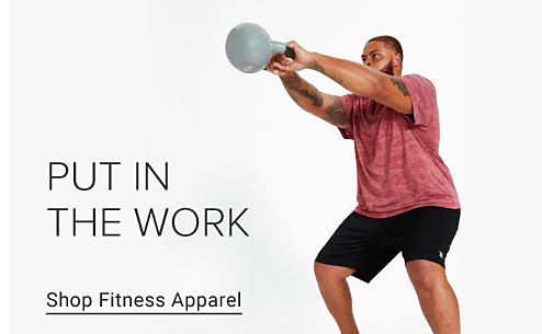 A man in a red shirt and black shorts lifts a kettle bell. Put in the work. Shop fitness apparel.