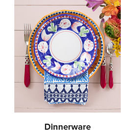 A plate with a blue border set on a table alongside silverware. Shop Dinnerware.