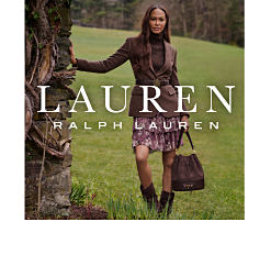 A woman wearing a blazer, a skirt and boots and holding a handbag. Shop Lauren Ralph Lauren.