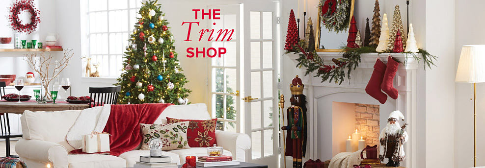 A living room with a Christmas tree and various other Christmas decor on the mantel and couch. The Trim Shop.