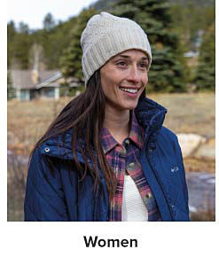 A woman wearing a grey knit hat, a flannel shirt and blue jacket. Shop women.