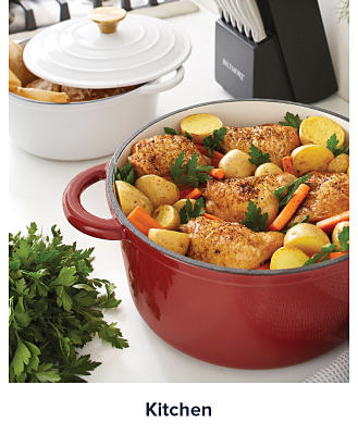 A red Dutch oven filled with chicken, potatoes and carrots. Shop kitchen. 
