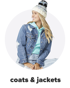 A young woman wears a knit hat and a denim jacket over a light blue sweatshirt. Shop coats and jackets.
