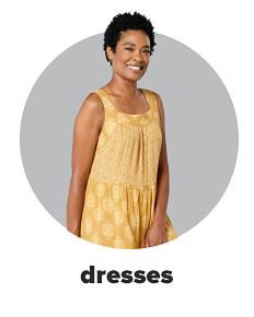 A woman wears a yellow, printed dress. Shop dresses.