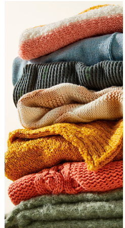 A stack of various sweaters in different colors and textures. 