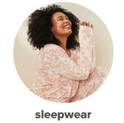 A woman in a light pink and white leopard print pajama set. Shop sleepwear.