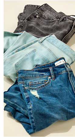 3 pairs of jeans in various shades folded on a surface.