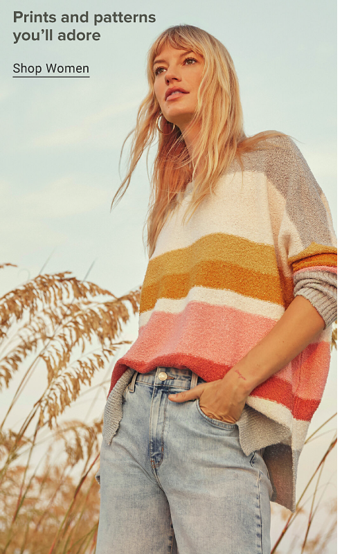 A woman in a light gray, yellow, orange and pink striped sweater with light jeans. Prints and patterns you'll adore. Shop women.