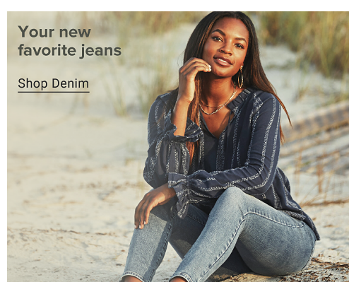 A woman sitting on the beach in a vertical striped navy and white blouse with skinny jeans. Your new favorite jeans. Shop denim.
