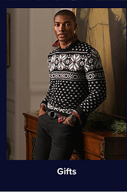 An image of a man wearing a holiday-patterned sweater. Shop gifts.