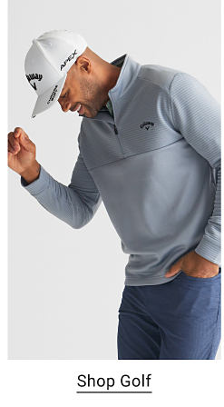 An image of a man wearing a grey pullover shirt, blue golf pants and a white hat. Shop golf.