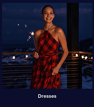 An image of a woman in a red and black dress holding a fireworks sparkler. Shop dresses.
