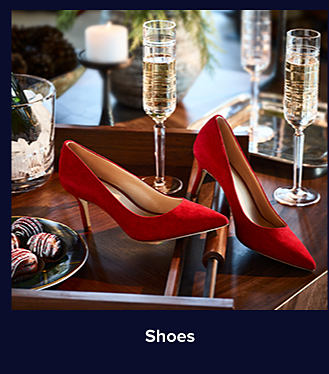 An image of a pair of red heels on a table. Shop shoes.