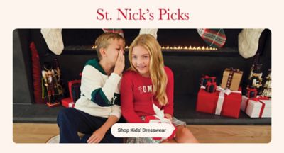 Image of a young boy and girl sitting in front of presents. St. Nick's Picks. Shop kids' dresswear. 